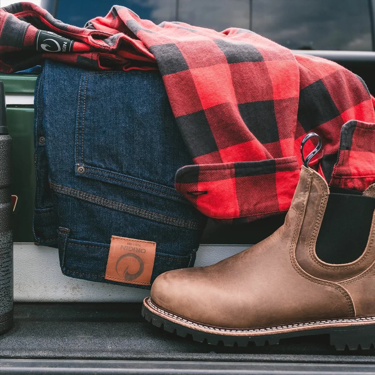 Origin boots, jeans and a flannel shirt in the back of a truck